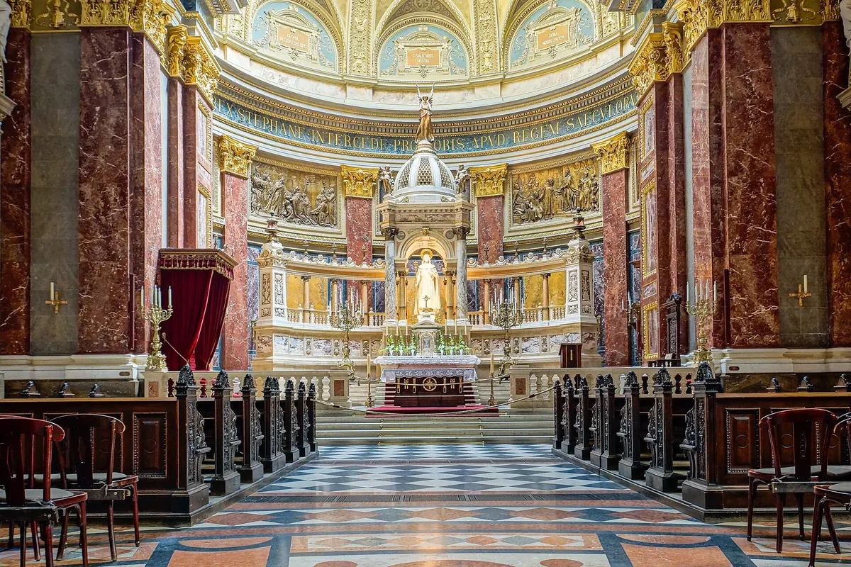 The high altar of St Stephen's Basilica seen along a marble floor, with a canopy over a statue of the saint and red marble columns on either side.