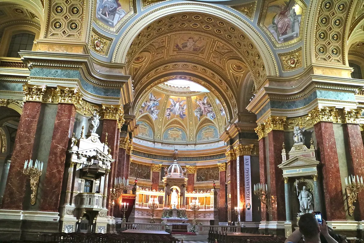 Looking along the nave of St Stephen's Basilica towards the sanctuary, with pews, pillars faced in marble and the dome beyond
